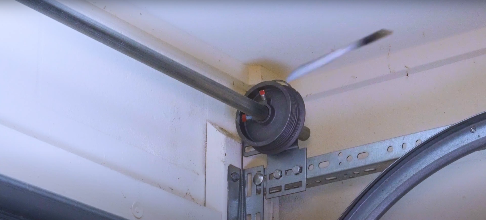 A garage door technician replacing a frayed or broken cable on a residential garage door system.