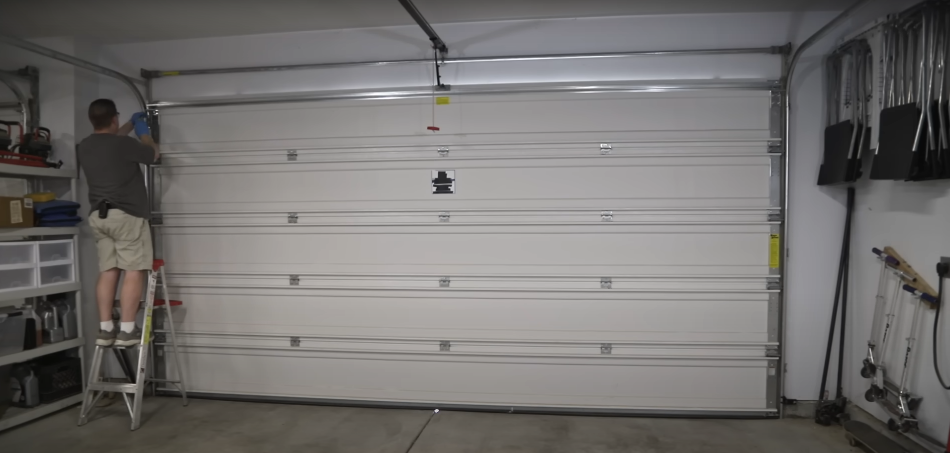 A technician performing same-day garage door repair on a residential house.