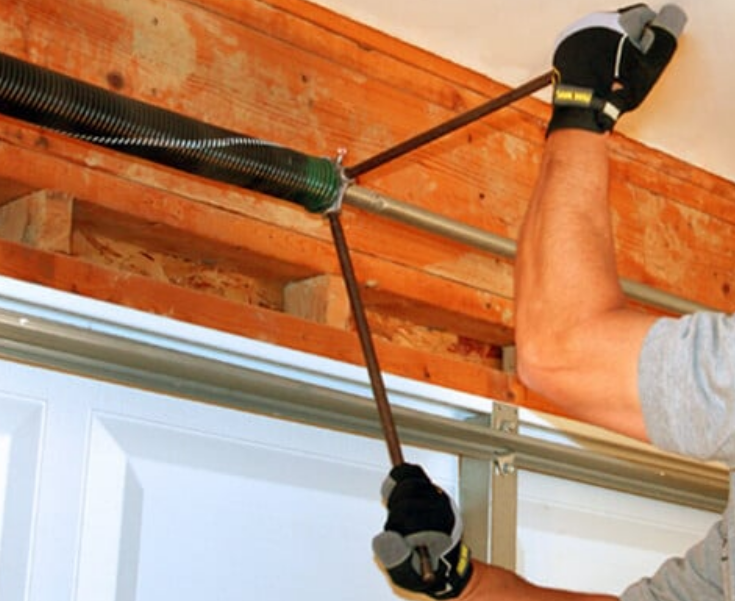 Close-up of a technician adjusting a garage door spring with tools in Cape Coral, FL, highlighting professional garage door repair services.