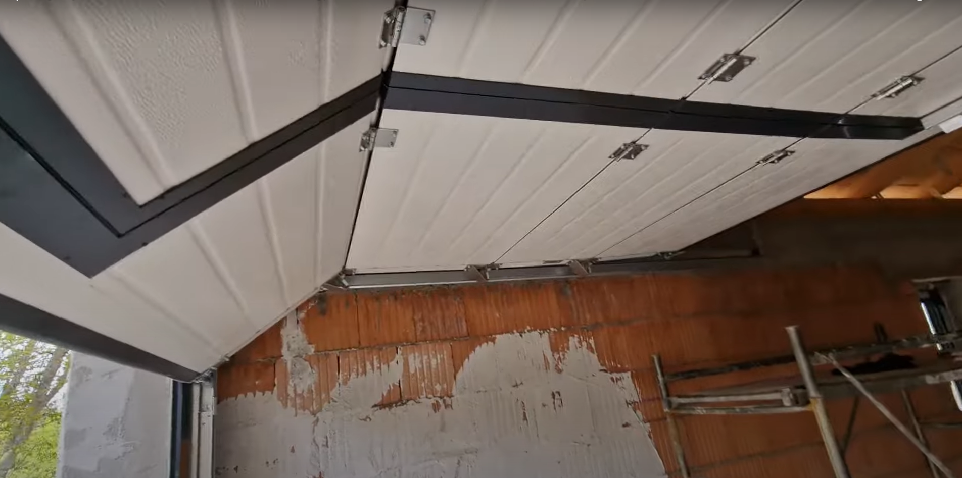 A technician in a blue uniform repairing the springs of a residential overhead garage door.