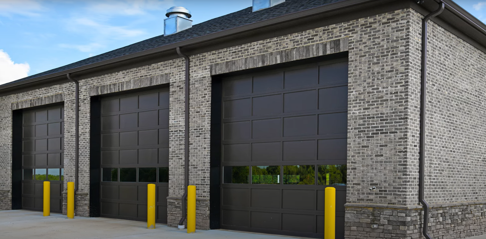 A technician repairing a large metal overhead garage door at a commercial warehouse.